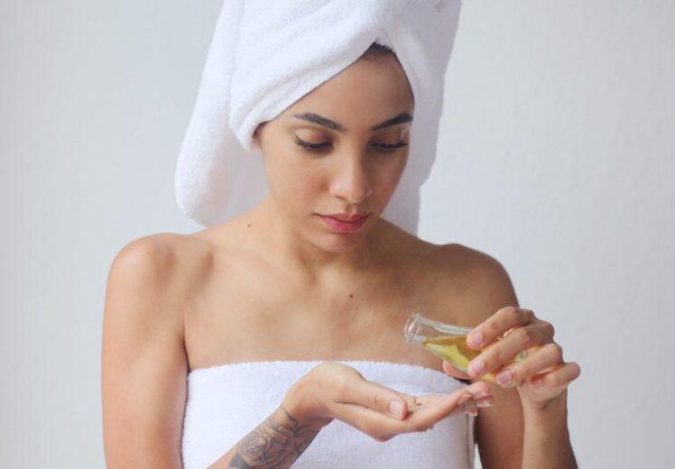 A girl uses oil to rejuvenate her skin